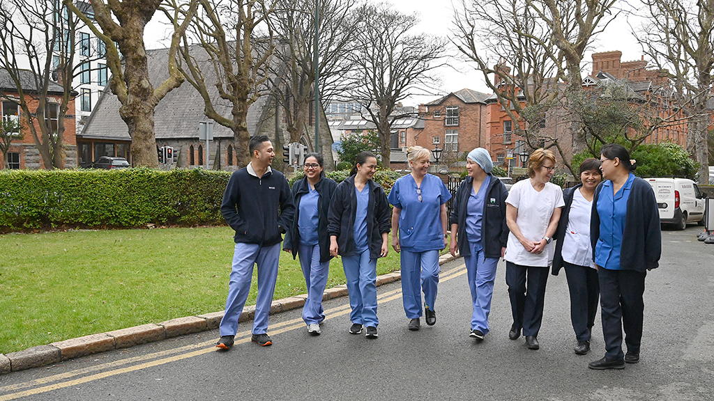a group of nurses in uniform outside the eye and ear hospital walking and chatting